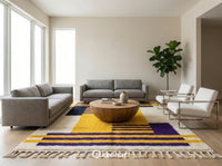 Large custom Moroccan area rug anchoring a modern bohemian living room with a neutral linen sofa, highlighting the bold indigo and yellow diamond motif.