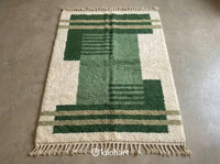 Custom made Beni Ourain Moroccan wool rug featuring plush texture and geometric diamond pattern in shades of Pesto, Russian, and Sage Green with traditional fringe.