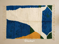Custom made-to-order Beni Ourain Moroccan wool rug showing plush texture, traditional fringe, and geometric diamond patterns in blue, soft white, aztec gold, and fir green.